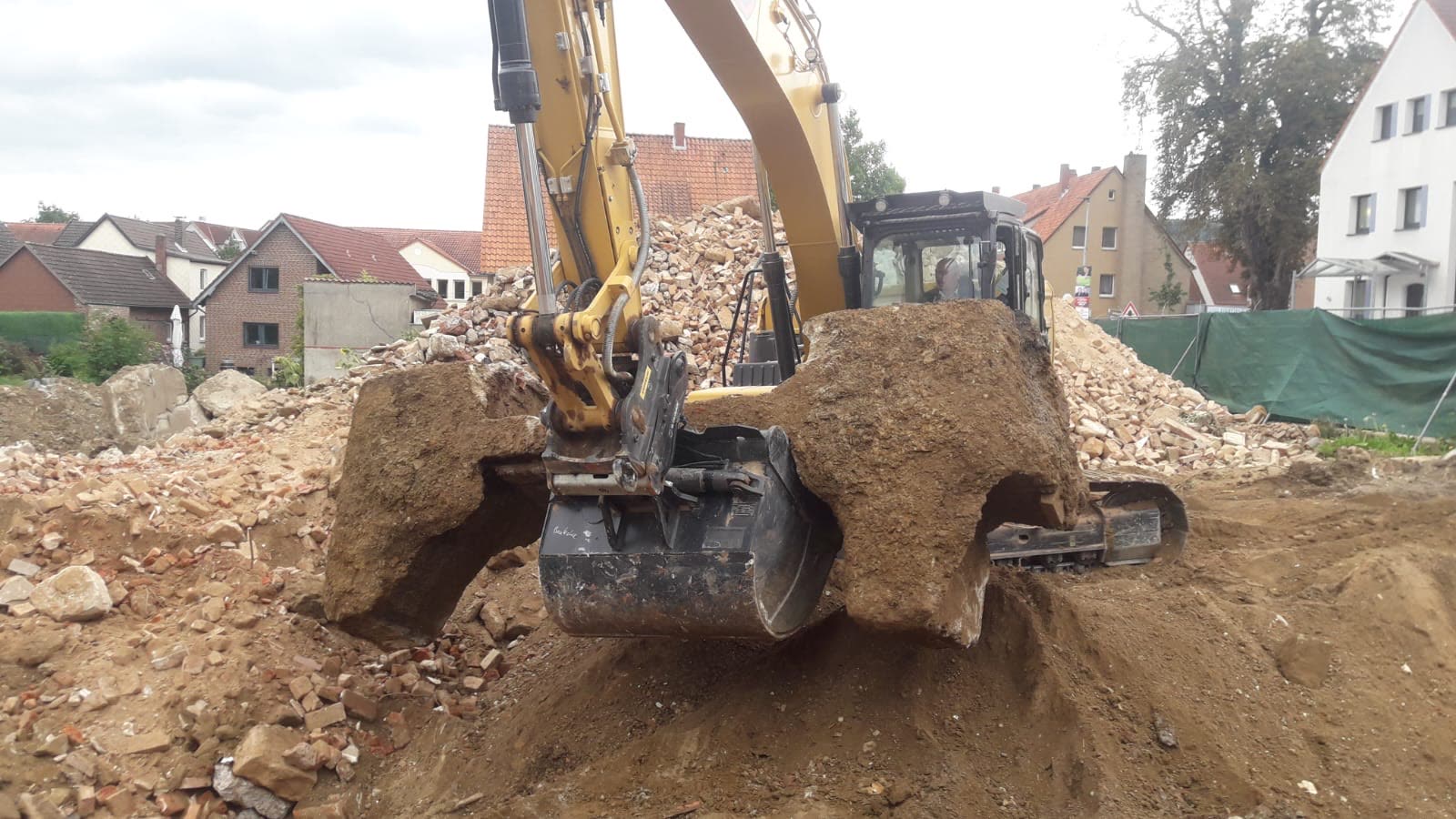 Bagger hebt Bodenmaterial aus einer Baugrube